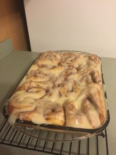 a pan filled with cinnamon rolls sitting on top of a metal rack next to a counter