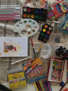 the table is covered with art supplies such as crayons, pencils and markers