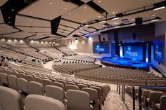 an empty auditorium with rows of seats facing the stage and projection screen on the wall