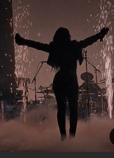 a woman standing in front of a stage with her arms outstretched