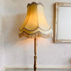 a lamp sitting on top of a wooden table next to a mirror and framed photograph