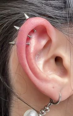 a close up of a person's ear with metal spikes and pearls on it