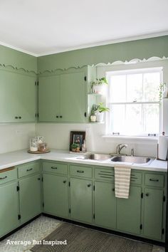 a kitchen with green cabinets and white counter tops is pictured in this image, there are plants on the window sill above the sink