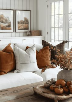 a living room filled with white couches and pillows on top of a wooden table