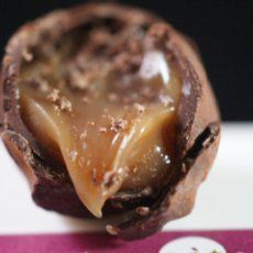 a chocolate dessert with caramel filling on a pink and white plate next to a sticker