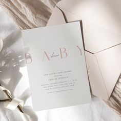 the baby announcement card is laying on top of some white paper with pink lettering and ribbon