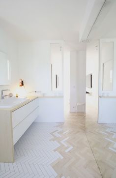 a white bathroom with two sinks and mirrors on the wall, along with tiled flooring