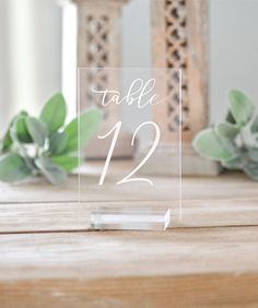 a clear acrylic sign with the words table 20 on it sitting next to succulents