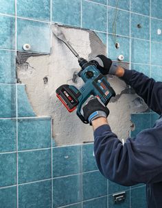 a man is using a drill to fix a hole in the wall with a hammer