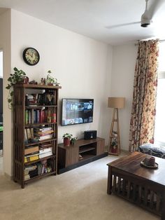 a living room filled with furniture and a flat screen tv on top of a wooden shelf