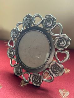 an ornate silver ring with roses on the front and center is sitting on a red tablecloth