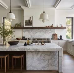 a kitchen with marble counter tops and wooden stools in front of an island that has two hanging lights above it