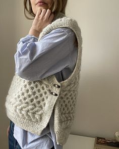 a woman is leaning against a wall with her hand on her chin