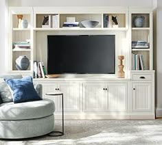 a living room filled with furniture and a flat screen tv mounted on a white wall