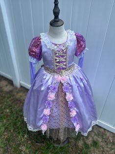 Transform your little one into a fairy tale princess with this enchanting lilac dress, perfect for special occasions and dress-up play. Crafted with love and meticulous attention to detail, this dress is sure to make dreams come true. ✨ **Features 🌸 **Elegant Design Lavish lilac satin fabric adorned with delicate lace and floral accents. 💫 **Sparkling Details Glittery sequin puff sleeves add a touch of magical sparkle. 🎀 **Lace-Up Bodice Intricate lace-up front with pearl embellishments for a Lavender Fitted Princess Dress For Dress-up, Lavender Tulle Princess Dress For Dress-up, Lavender Princess Dress For Dress-up, Princess Style Lavender Fairy Dress For Party, Lavender Princess Dress For Party, Lavender Princess Dress For Dress-up Occasions, Elegant Lavender Princess Dress For Dress-up, Fairy Style Purple Wedding Dresses, Purple Fairy Style Wedding Dress