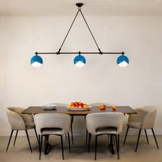 a dining room table with four chairs and a bowl of fruit on the plate in front of it