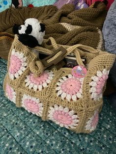 a crocheted purse sitting on top of a bed next to a pile of blankets