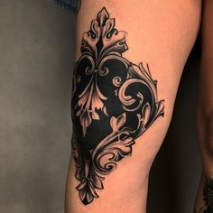 a woman's thigh with an ornate black and white tattoo design on her leg