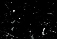 black and white photograph of shattered glass in the dark, with small pieces missing from it