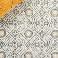 the fabric is yellow and grey with an intricate design on it, along with some white circles