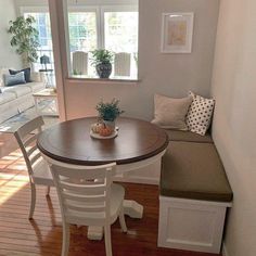 a dining room table with two chairs and a bench in front of the window,