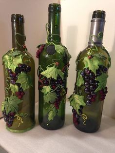 three wine bottles with grapes painted on them