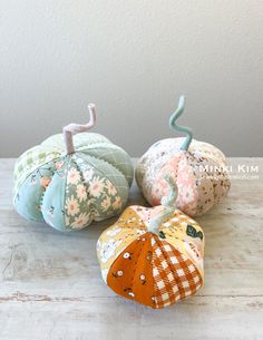 three fabric pumpkins sitting on top of a wooden table next to eachother