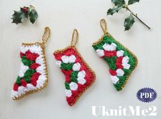 three crocheted christmas stockings hanging from hooks on a white surface next to holly branches