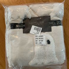 two pairs of white socks in plastic wrap on wooden floor with price tag for each pair