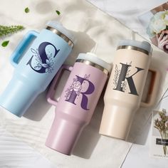 three personalized travel mugs sitting next to each other on a white tablecloth