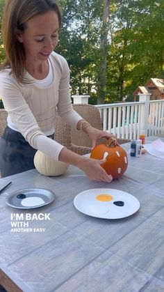 a woman sitting at a table carving a pumpkin