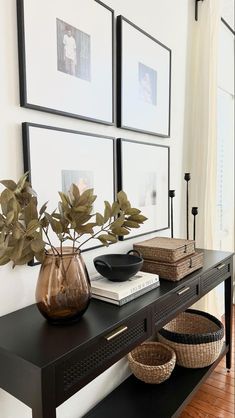 a black table topped with vases filled with flowers next to pictures on the wall