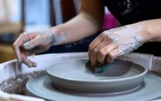 a woman is working with clay on a potter's wheel