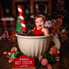 a baby is sitting in a bowl with chocolate and candy canes on the table