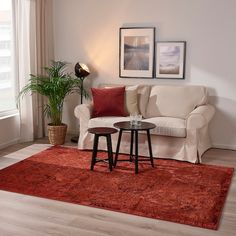 a living room with a white couch and red rug on the floor next to a window