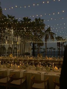 a long table is set up with candles and flowers in front of palm trees at night