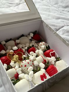 an open box filled with marshmallows and other candies on top of a bed