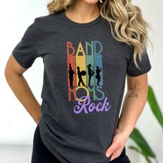 Looking for the perfect t-shirt to show off your love for your child's band? Look no further! This comfortable and stylish shirt is the perfect choice for any proud band mom. Featuring the trendy design "Band Moms Rock", this shirt is sure to turn heads and show your support for your child's musical endeavors. The Bella Canvas 3001 t-shirt is made from high-quality materials that are soft and breathable, so you'll stay comfortable all day long. Whether you're attending a band concert or just run Pop Culture Shirt With Letter Print For Concerts, Pop Culture Letter Print Shirt For Concerts, Rock And Roll Cotton T-shirt With Band Logo, Cotton Rock And Roll T-shirt With Band Logo, Cotton Tri-blend Tops With Band Logo, Music-themed Slogan Tops For Concerts, Unisex Band Logo T-shirt For Concerts, Band Merch Shirt With Slogan For Concerts, Pop Culture Cotton Top With Band Logo