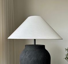 a black vase with a white shade on it