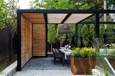 an outdoor dining area with wooden slatted walls and table surrounded by potted plants