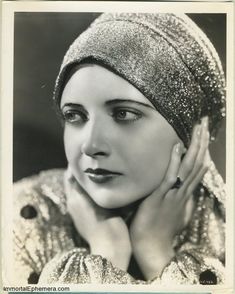 an old black and white photo of a woman with her hands on her chins