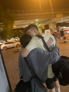 two people hugging each other on the street