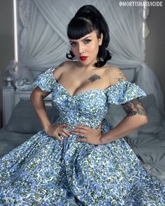 a woman in a blue dress with tattoos on her arm and chest posing for the camera