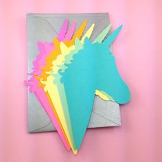 a unicorn head cut out of paper on a pink background