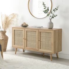 a wooden cabinet with wicker doors and a round mirror on the wall above it