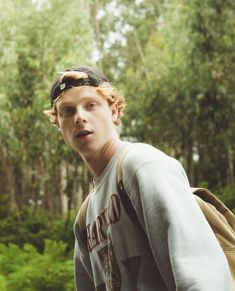 a young man is standing in the woods