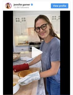 a woman in glasses is making pancakes on a counter top and smiling at the camera