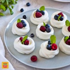 small desserts are arranged on a plate with berries and mint garnishes