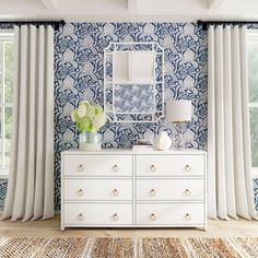 a white dresser sitting next to a window covered in blue and white wall coverings