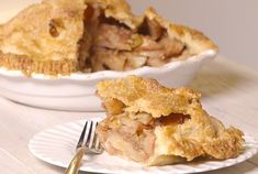 a piece of pie sitting on top of a white plate next to a fork and bowl